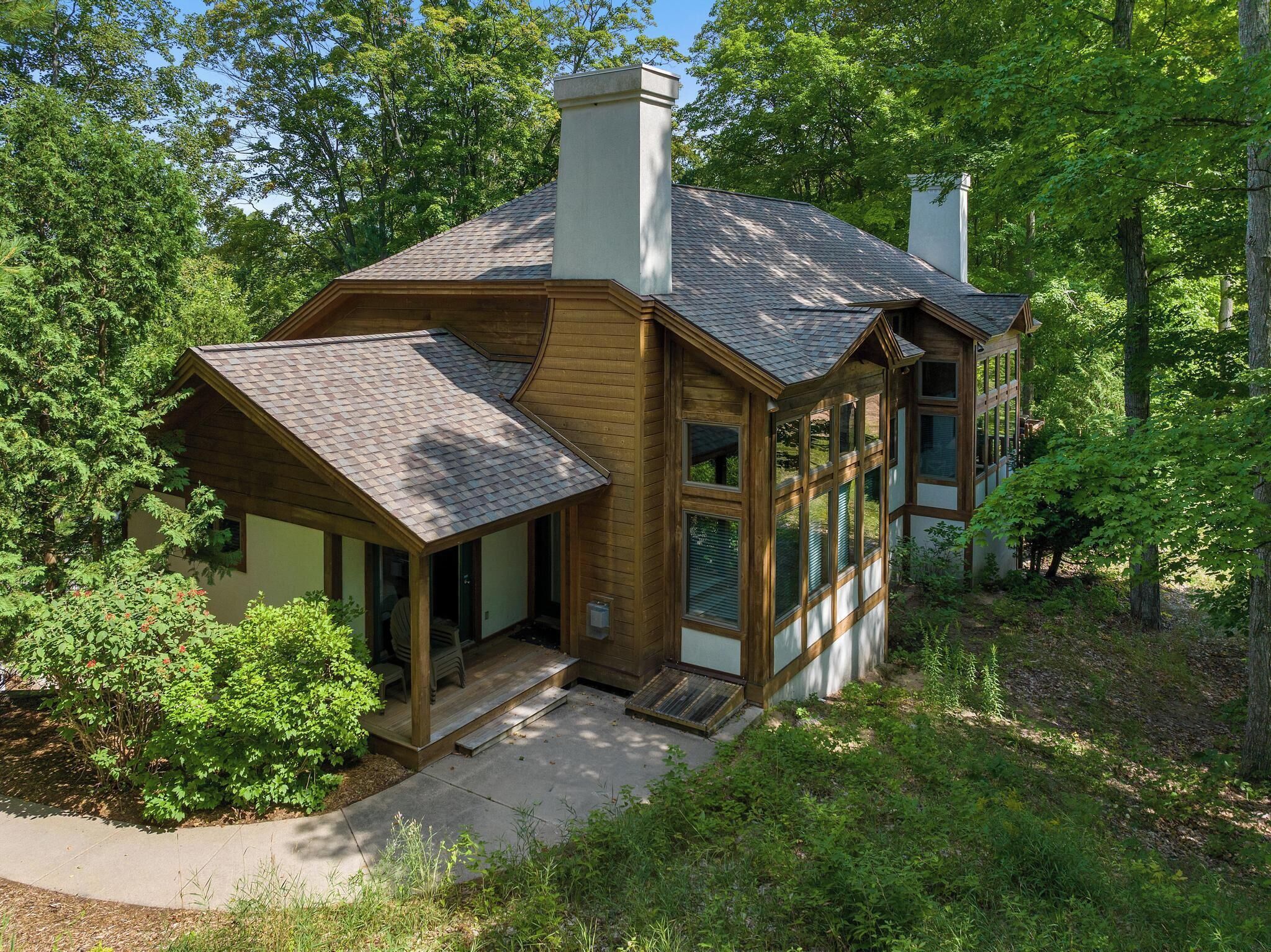 Ein zweistöckiges Holzhaus mit einer Veranda, großen Fenstern und einem Schornstein.