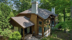 Une maison en bois à deux étages, dotée d’un porche abrité, de grandes fenêtres et d’une cheminée.