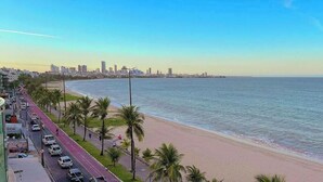 Eine Küstenstadt mit Strand, einer Straße mit Autos und einem Stadt-Hintergrund.