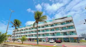 A multi-story hotel with balconies, a parking area, and palm trees. - Manaíra Palace - Michel  (João Pessoa)