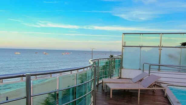 Ein Balkon mit Meerblick, ein Poolbereich und eine Glaskonstruktion.