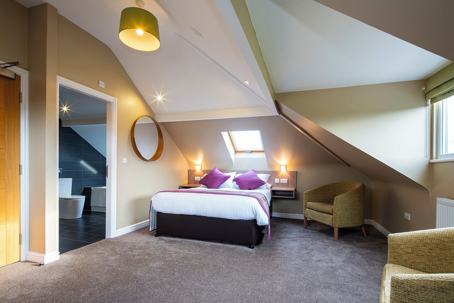 A bedroom with a bed, a chair, a skylight, and a staircase.