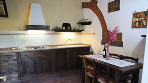 Una cocina con salpicadero de azulejos, armarios de madera, estufa a gas y un comedor con mesa y sillas.