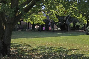A park with a grassy area, trees, and a fence in the background.