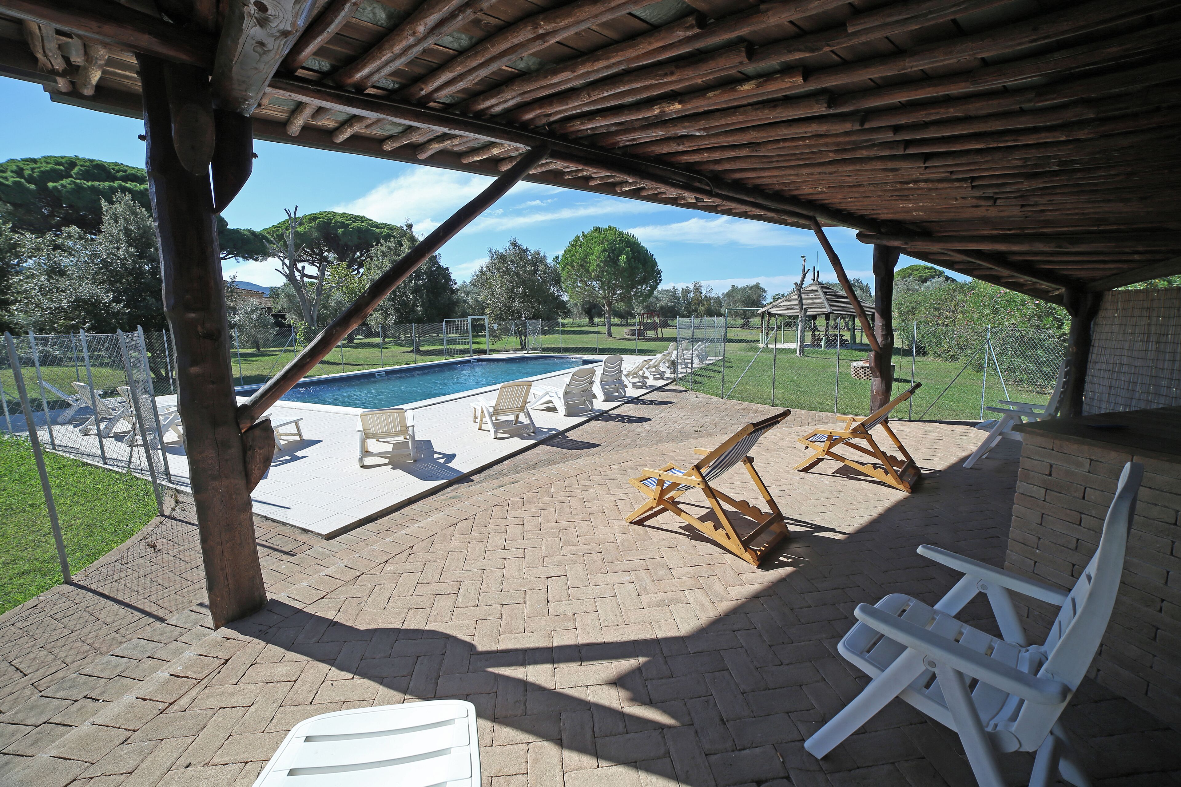 Zona exterior coberta amb piscina, gandules i terrassa de maó.