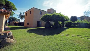 Un edificio con techo plano, una ventana pequeña y una puerta. Hay un árbol delante del edificio.