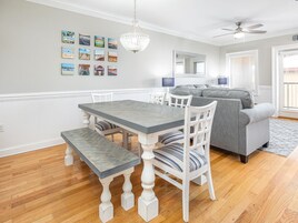 Un espace repas comprenant une table et des chaises, un banc, un canapé, un lustre et un ventilateur de plafond.