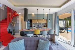 Ein modernes Interieur mit Essbereich, Küche und einer roten Treppe.