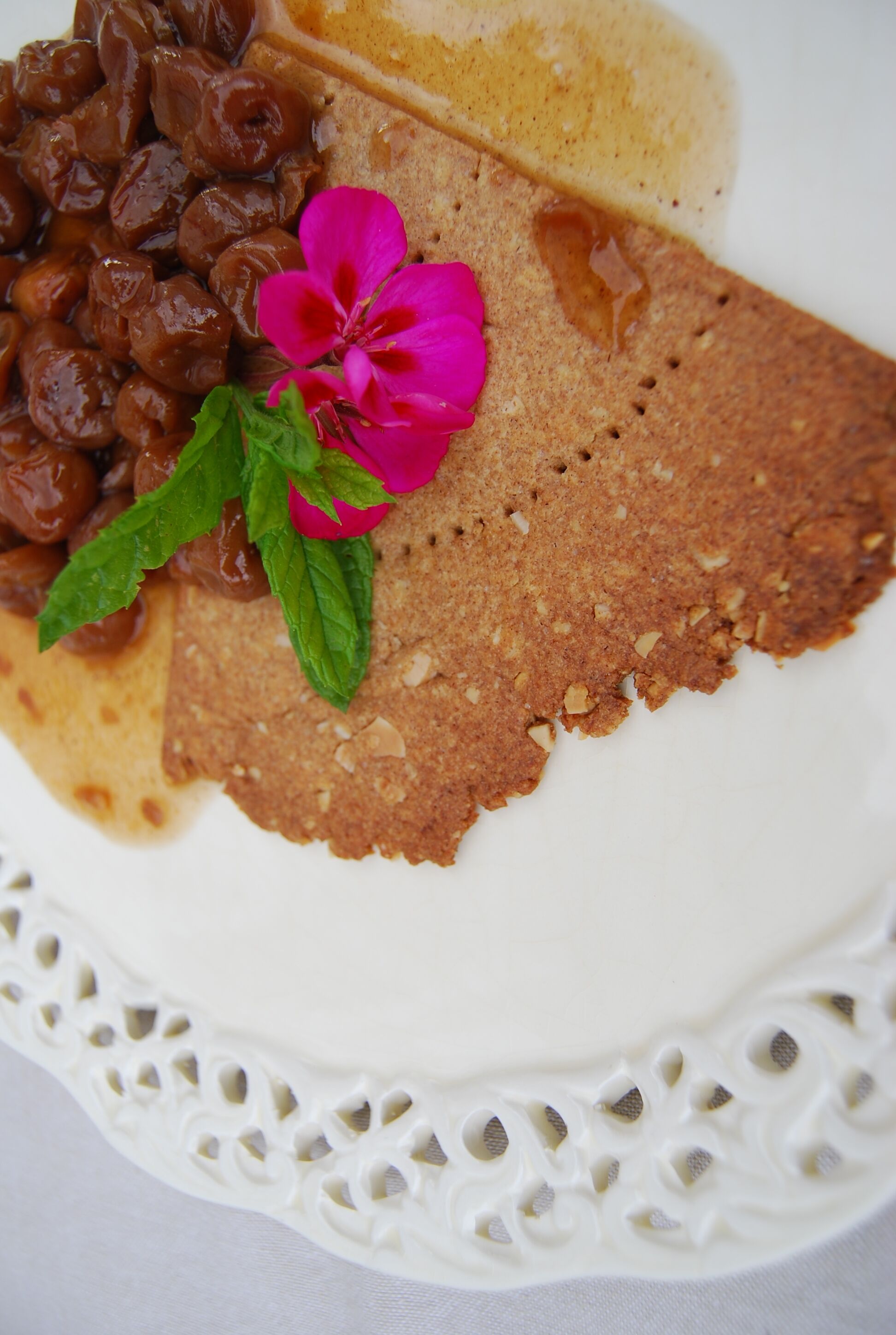 A plate with a slice of cake, a dollop of cream, and a flower.