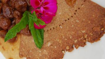 A plate with a slice of cake, a dollop of cream, and a flower.