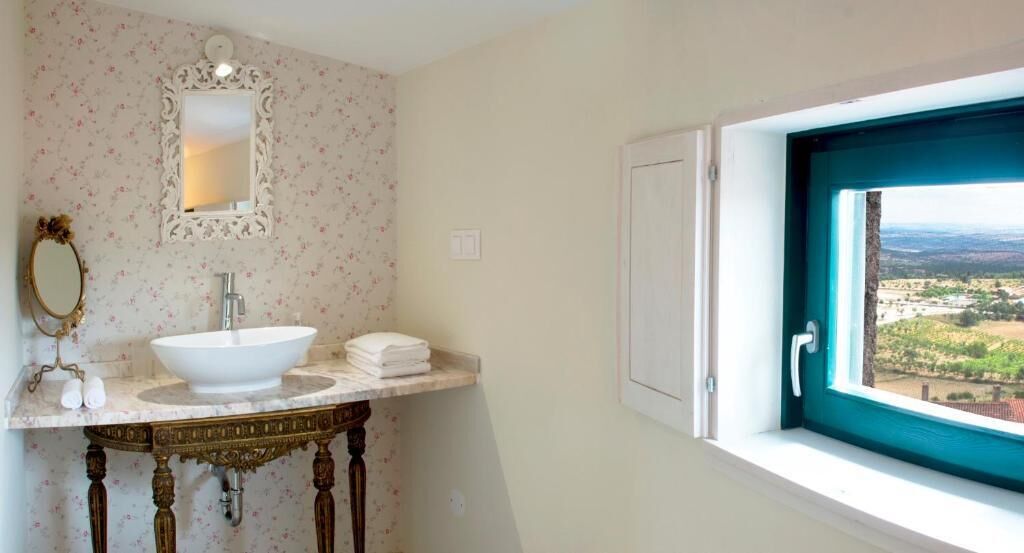 A bathroom with a sink, mirror, and window with a view.
