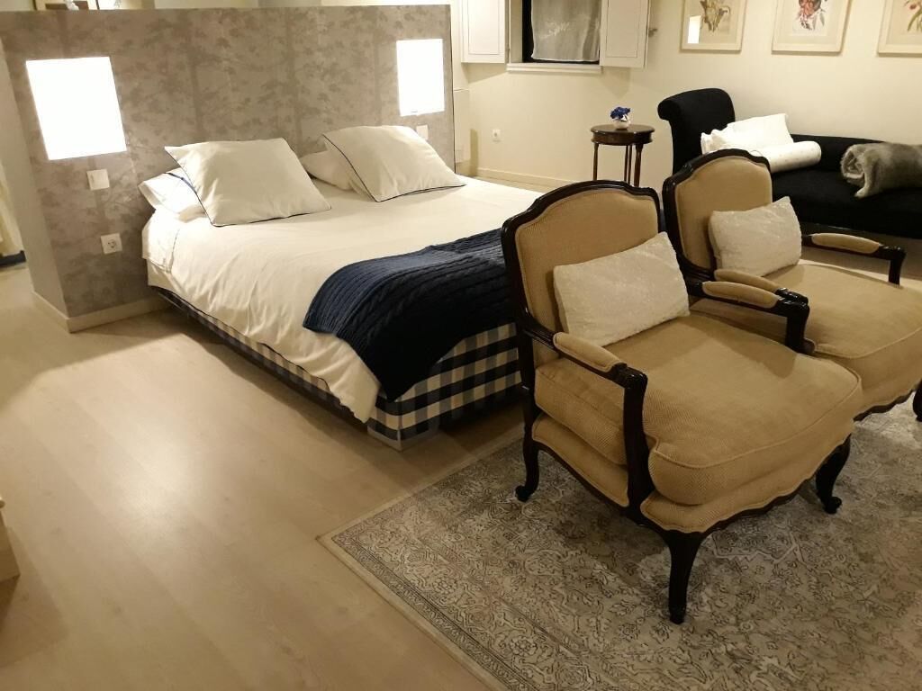 Un dormitorio con una cama, dos sillones, una mesita y una alfombra.