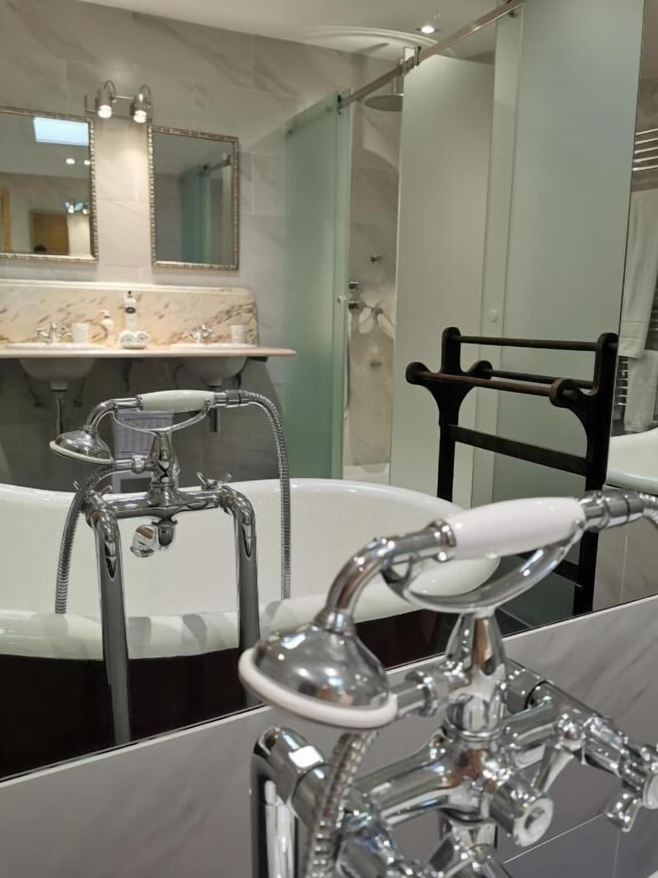 A modern bathroom with a large bathtub, a separate shower area, and a mirror above the sink.