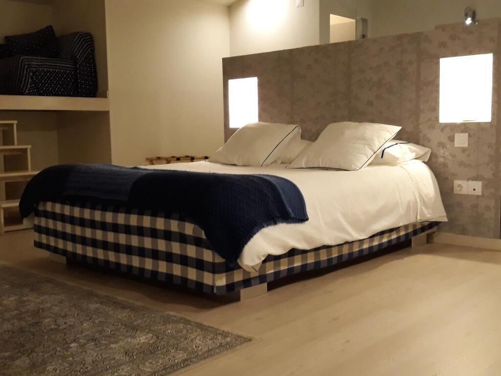Una cama con colcha de cuadros, dos almohadas y una manta azul.