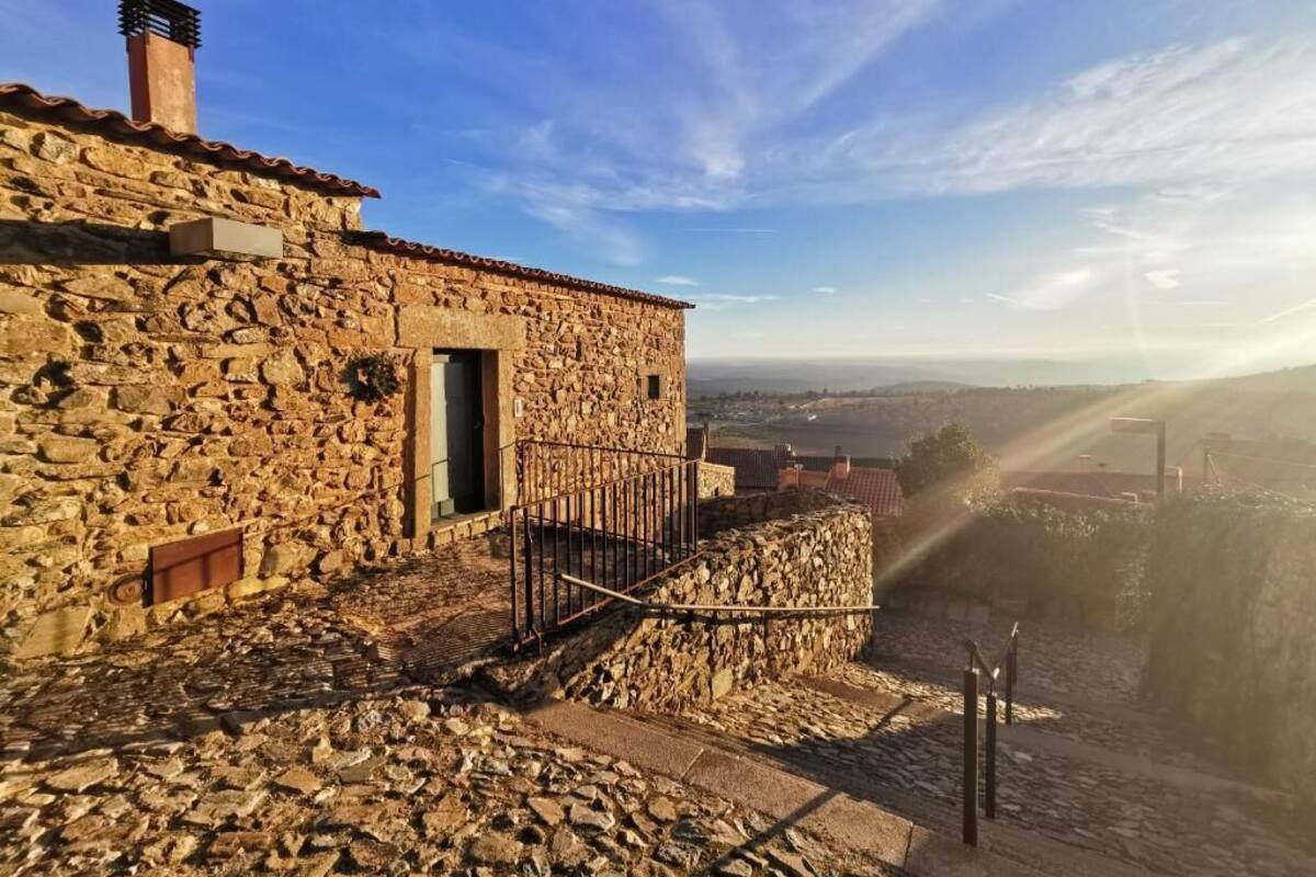 A stone building with a metal railing and a view of a distant landscape.