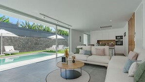 A modern living room with a pool, a sofa, a coffee table, and a kitchen area. - Standard Villa 2 - Casangular by Upper (Adeje)