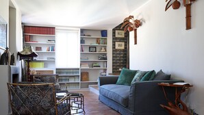 Un saló amb un sofà, una butaca i una biblioteca.