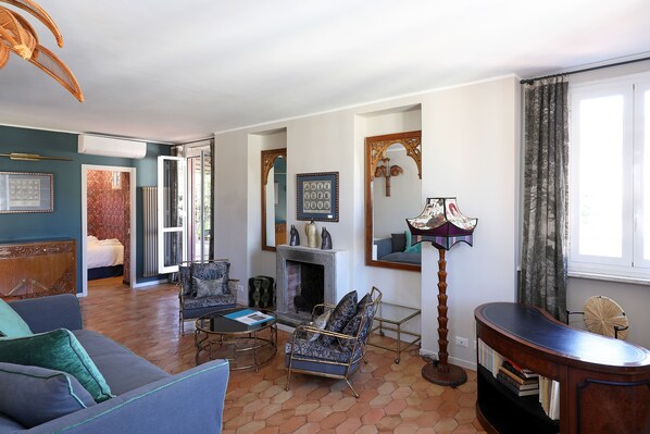 A living room with a sofa, armchair, fireplace, and a large mirror. - Historic apartment with a terrace and a view of the city (Roma)