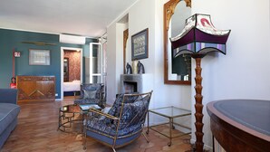 Habitació amb paret blava, un armari de fusta, un relaxant blau, una taula, una làmpada de peu i un mirall.