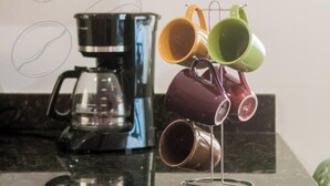 Eine Küche mit Kaffeemaschine, Tassenhalter und zwei gerahmten Bildern an der Wand.