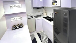 A modern kitchen with white cabinetry, a black refrigerator, a microwave, and a coffee machine. - Welcome to Lucky7suites (Parañaque)