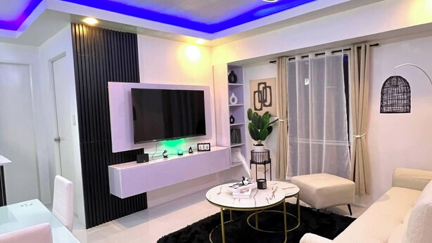 A modern living room with a flat-screen TV, a round coffee table, and a sofa. - Welcome to Lucky7suites (Parañaque)