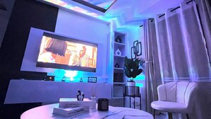 A modern living room with a flat-screen TV, a round coffee table, a white sofa, and a potted plant. - Welcome to Lucky7suites (Parañaque)