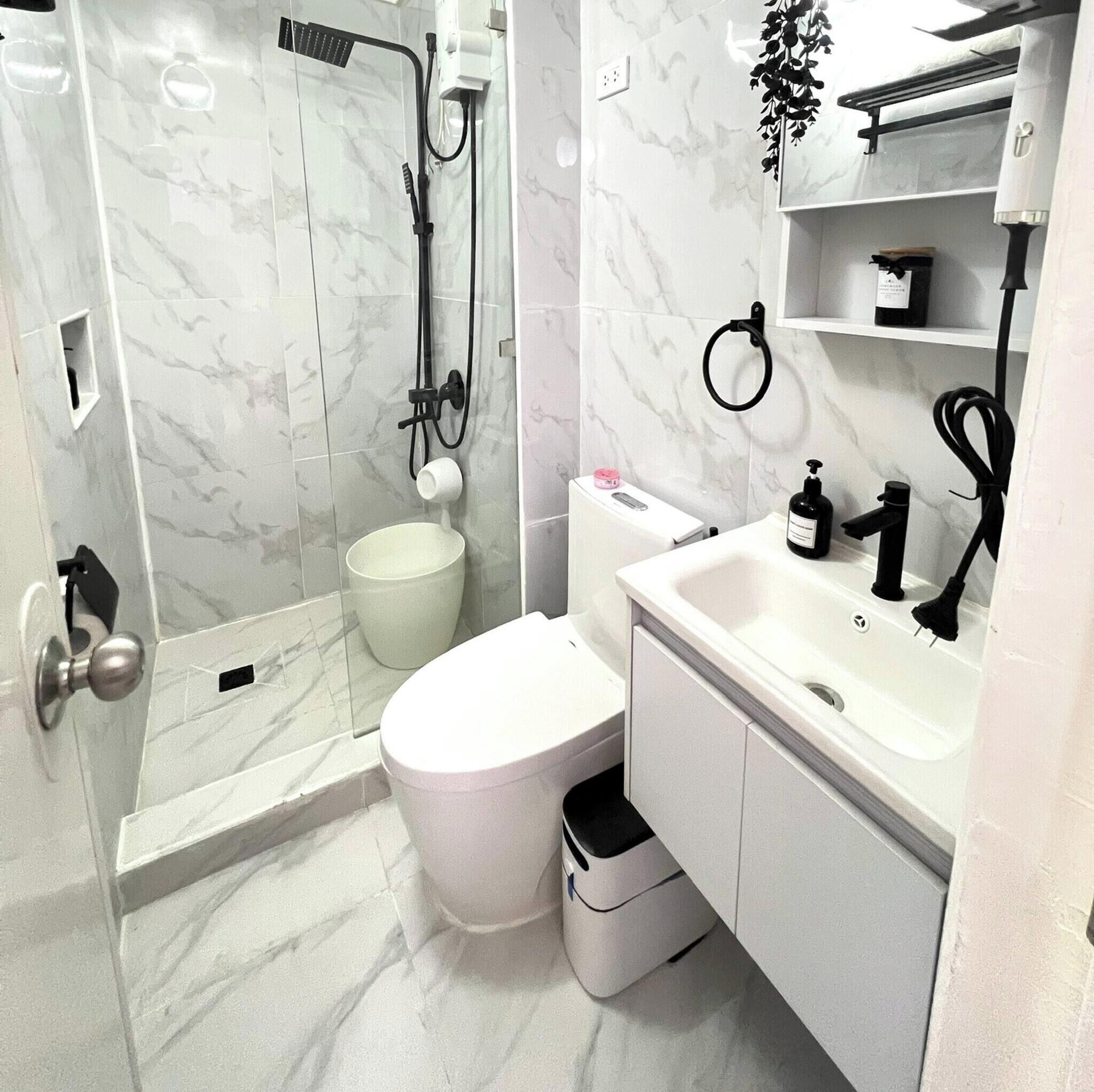 A bathroom with a shower, toilet, sink, and storage cabinet.