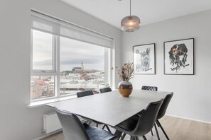 A dining area with a table, chairs, a vase with flowers, and framed artwork on the wall. - City centre premium apartment with free parking (Reykjavík)