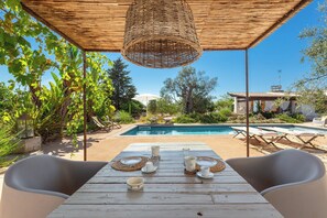 A wooden table set for dining with a pool and lounge chairs in the background. - 5 minutes from beaches Room with shared pool in Salento, Puglia (Salve)