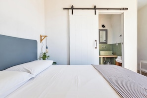A bedroom with a bed, a nightstand, a plant, a sliding door to a bathroom, and a mirror. - 5 minutes from beaches Room with shared pool in Salento, Puglia (Salve)