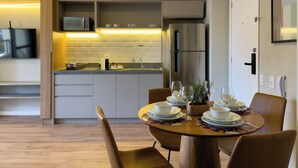 Uma cozinha moderna com micro-ondas embutido, geladeira e área de jantar com mesa posta para quatro pessoas.