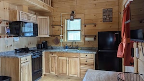 Une cuisine de style rustique, avec des meubles en bois, une cuisinière, un évier et un réfrigérateur.