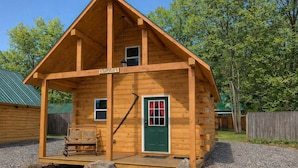Une cabane en bois avec un porche, une porte verte et une enseigne sur laquelle on peut lire « NORTHWOOD ».