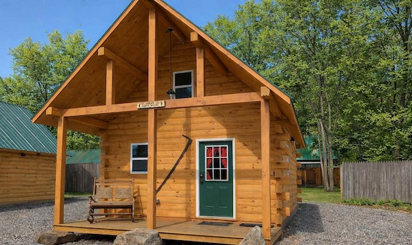 A wooden cabin with a porch, a green door, and a sign that reads 'NORTHWOOD'.