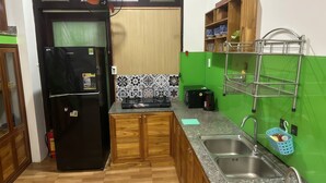 A compact kitchen with a black refrigerator, wooden cabinets, a gas stove, and a green backsplash. - 3BR Private Villa with Pool – Walk to Beach, Hoi An (Hoi An)