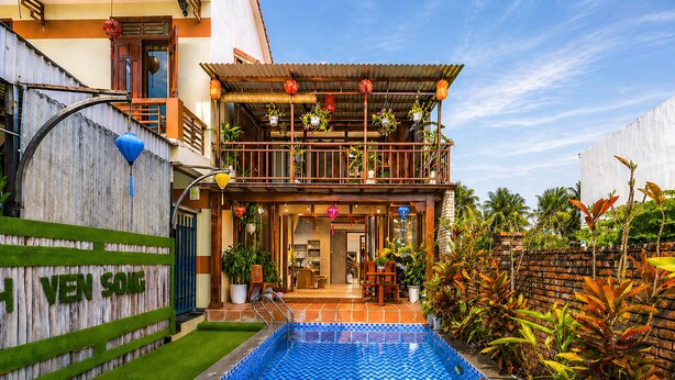 Un bâtiment à deux étages doté d’une piscine, d’un balcon agrémenté de plantes et d’une enseigne sur laquelle on peut lire « VEN SOLE ».