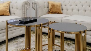 Ein Wohnzimmer mit einem weißen Sofa, zwei Beistelltischen und einem gerahmten Bild an der Wand.