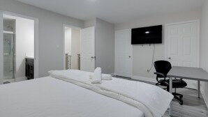 Ein Hotelzimmer mit einem großen Bett, einem Schreibtisch, einem Stuhl, einem Fernseher und einer Dusche.