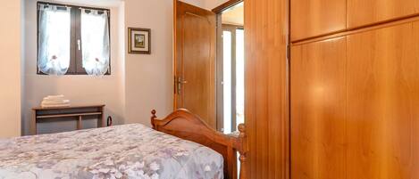 Une chambre à coucher avec un lit, une armoire en bois, une table de chevet et une fenêtre avec des rideaux.