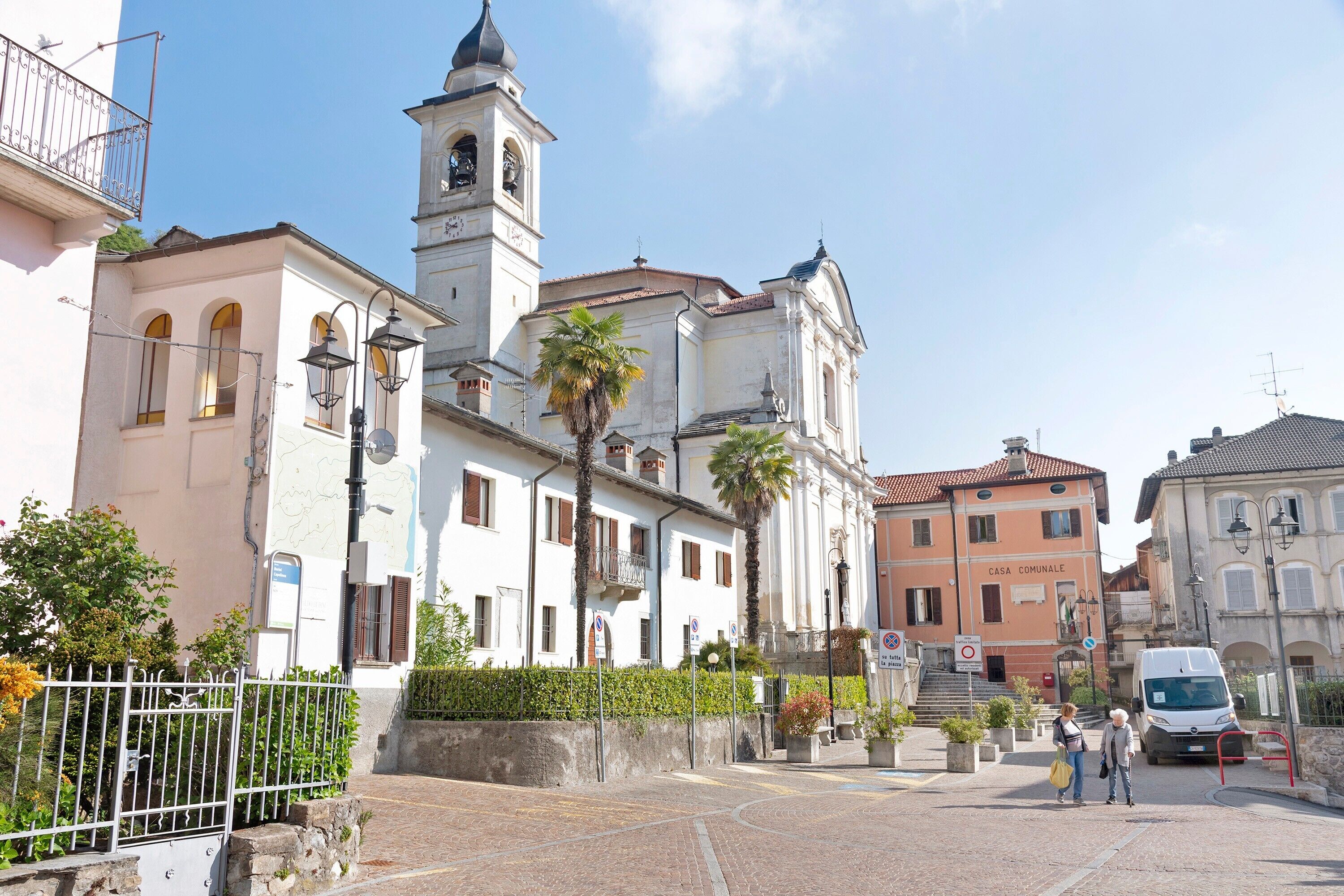 Una calle con edificios, una iglesia con un campanario y una furgoneta.