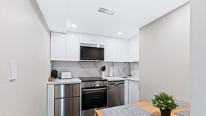 Eine moderne Küche mit Edelstahlgeräten, weißen Schränken und einem Holztisch mit einem Blumentopf.