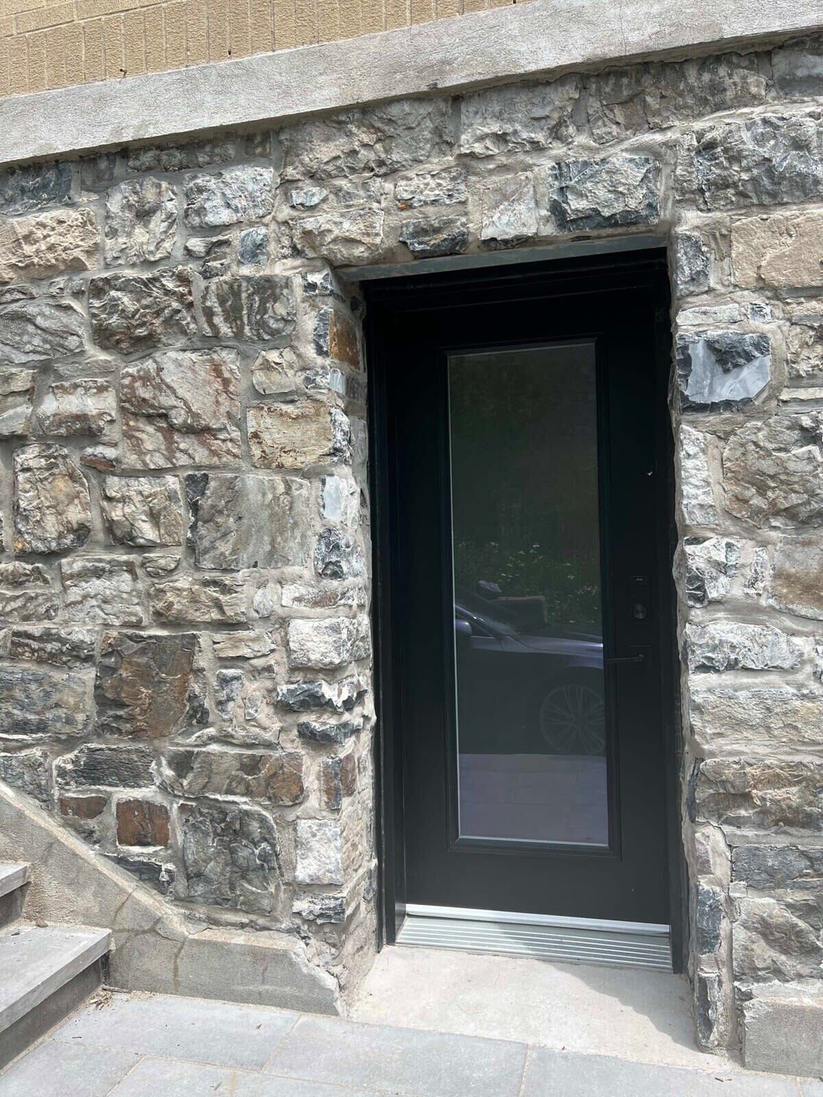 A stone building with a dark door and steps leading up to it.
