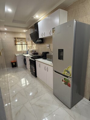 A modern kitchen with a stainless steel refrigerator, a microwave, and a stove. - 2-bed apt  in charming Lagos with AC WiFi, located at baruwa ipaja  (Lagos)
