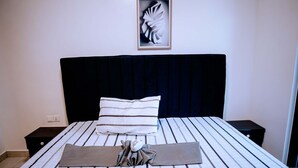 Un llit ben fet amb roba de llit a ratlles, un panell de capçal fosc, una almoçada i una tovallola doblegada.