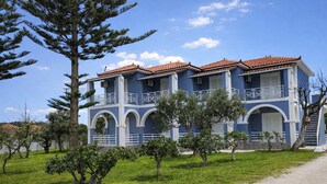 A two-story building with a blue facade, red-tiled roof, and white balconies.