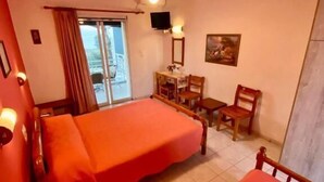 A hotel room with two beds, a desk, a chair, a television, and a balcony.