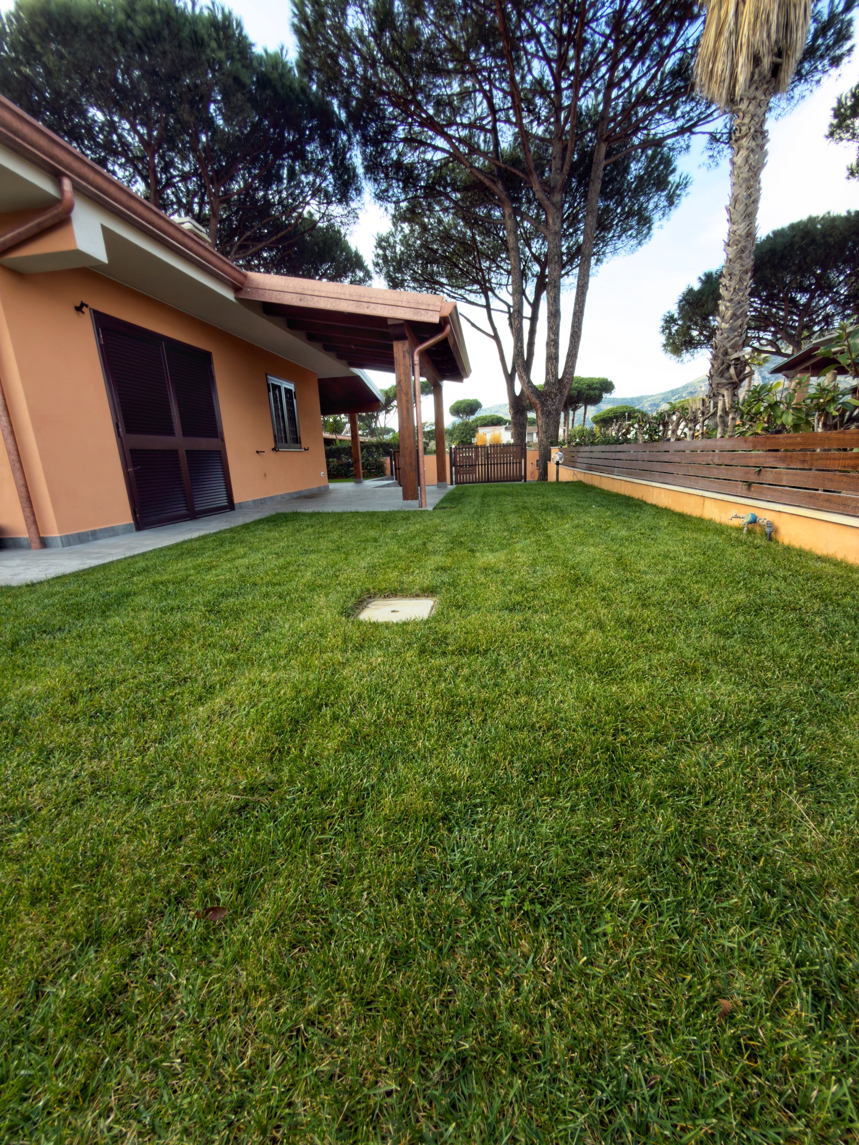 A residential property with a well-maintained lawn, a garage, and a covered patio area.