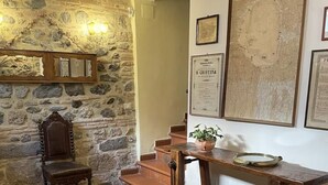 A stone wall, a wooden chair, a wooden table, and a map on the wall.