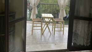 A room with a sliding glass door leading to an outdoor balcony with a table and chairs.